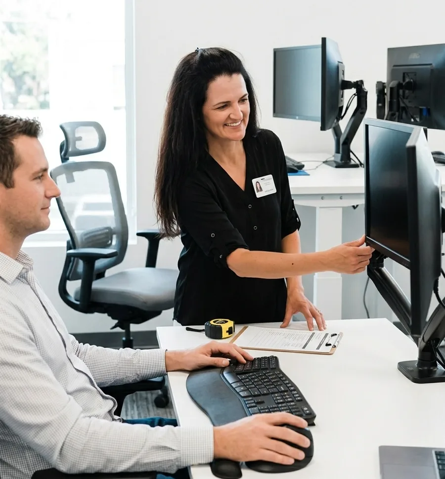 Ergonomics professional performing a workplace assessment with the Blueprint course open on a laptop